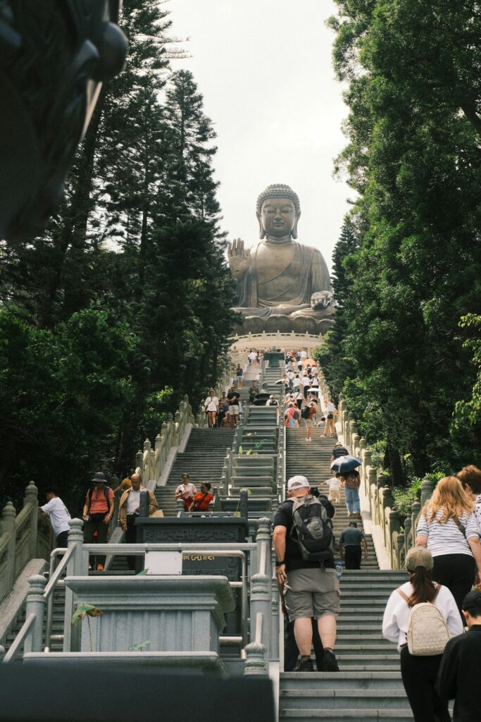 A large Buddha statue, the Tian Tan Buddha, sitting atop a hill, with a long staircase leading up to it.