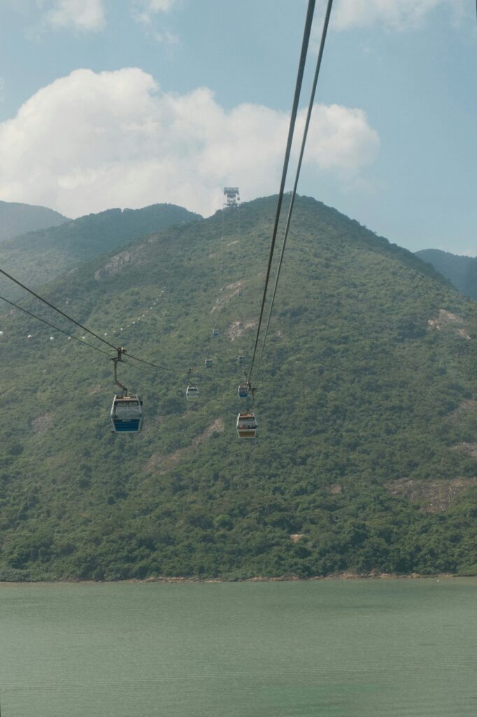 A cable car system stretching across green mountains, transporting visitors above a body of water.